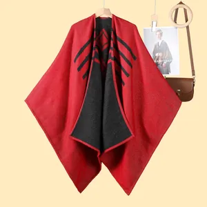 Dettaglio macro del poncho in maglia rosso e nero con motivi geometrici e trama spessa
