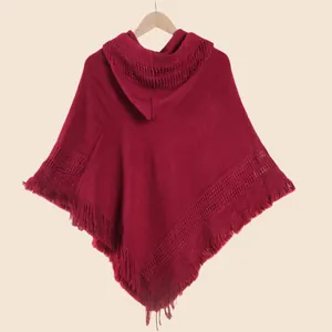 Détails du tricot d'un poncho rouge foncé à capuche avec finitions à franges