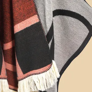 Détail d'un poncho géométrique avec texture en laine épaisse, bords finis et franges blanches