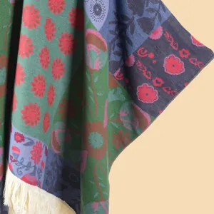 Detailed close-up of knit flower patterns and white tassels on a bohemian shawl
