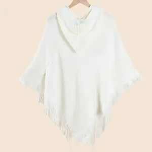 Gros plan détaillé du poncho blanc à capuche avec texture tricotée et longues franges