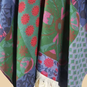 Detail of bohemian floral patchwork shawl with vibrant patterns and cream fringe accents