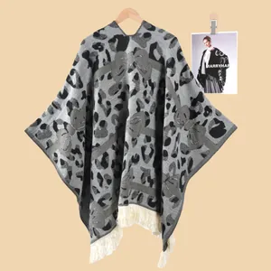 Detail von Leoparden- und Schleifenmuster auf grauem Strick-Poncho mit weißen Fransen