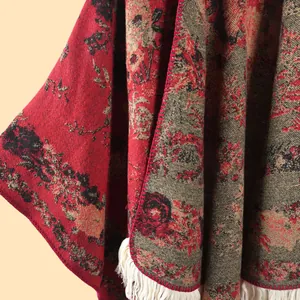 Detailed macro view of heavy jacquard floral pattern and white tassel fringe on thick shawl