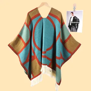 Détail du poncho en tricot à motifs géométriques avec des franges à pompons en crème