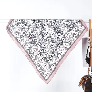Dettaglio di un foulard in seta appeso con bordo rosa e motivi a onde nere