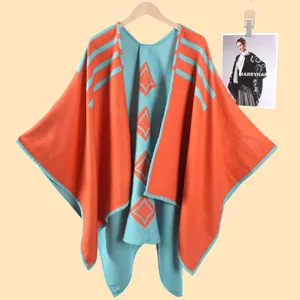 Dettaglio del poncho in maglia con motivi geometrici arancio e blu e trama a righe