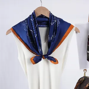 Pañuelo de seda azul con estampado paisley y borde naranja sobre top blanco