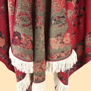 Close-up of thick floral knit shawl with vintage patterns and white tassel fringe detail