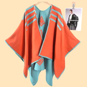 Dettaglio del poncho in maglia jacquard arancione e verde con motivi geometrici