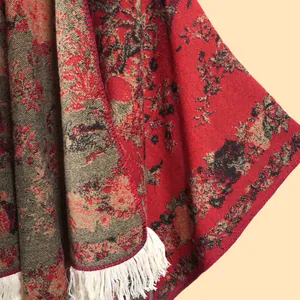 Macro detail of red vintage floral jacquard knit shawl with cream-colored long fringe