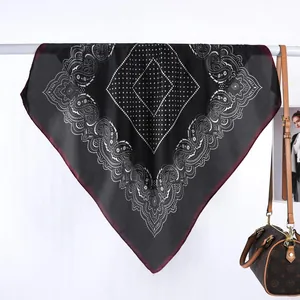 Detalle de bufanda de seda con estampado paisley negro y bordes de contraste granate