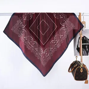 Detalle de cerca de un pañuelo de seda rojo oscuro con diseño de cachemira y lunares blancos