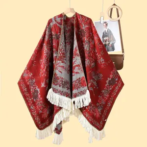 Floral knit poncho shawl in red and grey with long cream tassels on wood hanger