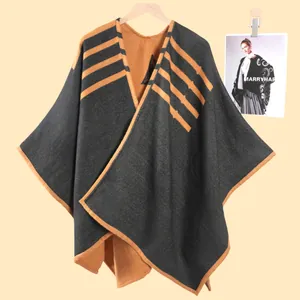 Dettaglio di un poncho grigio in maglia con strisce arancioni e texture morbida