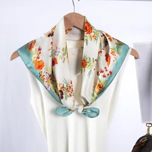 Élégant foulard en satin à fleurs crème et bleu sarcelle sur un gilet blanc