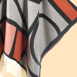 Détail macro du châle en tricot géométrique avec des franges épaisses et motifs colorés