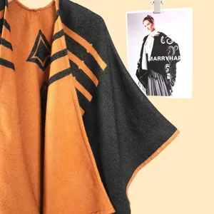 Dettaglio della trama a maglia del poncho a righe con motivi geometrici arancioni