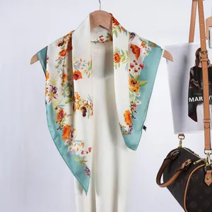 Élégant foulard en satin à fleurs beige et vert, drapé sur un cintre avec une robe blanche