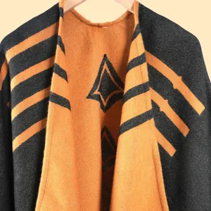 Dettaglio di uno scialle in maglia con motivi geometrici arancio e nero e trama fitta