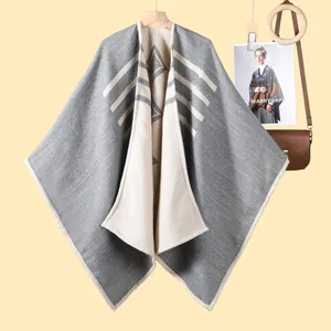 Dettaglio della maglia del poncho grigio e beige con motivo geometrico a strisce