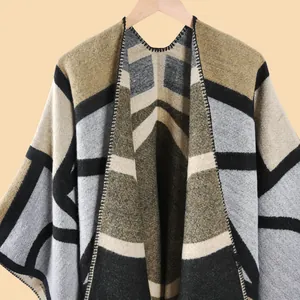 Gros plan du poncho en maille géométrique avec franges et détails de bordure soignés