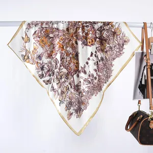 Détail d'un carré de soie avec d'élégants motifs de papillons et fleurs et bordure dorée