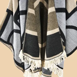 Détail d'un châle en tricot épais avec motifs géométriques et finitions à franges