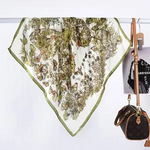 Détail d'un carré de soie imprimé papillons et fleurs drapé sur une barre avec un sac