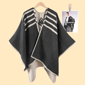 Dettaglio ravvicinato di poncho in maglia grigio scuro con motivi geometrici e bordi