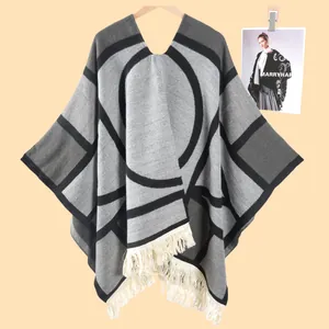 Détail de la maille du poncho géométrique avec des finitions à franges et pompons