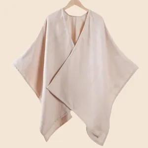 Dettaglio del morbido poncho a scialle rosa albicocca con delicato design a scollo a V
