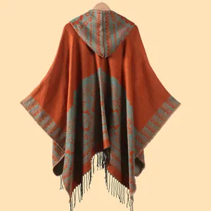Dettaglio dello scialle con cappuccio, motivi jacquard retrò e nappe con frange