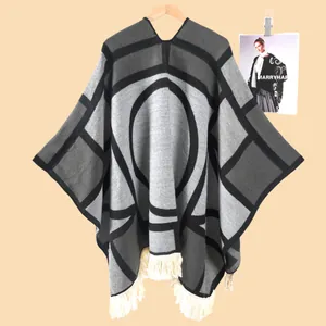 Detailaufnahme des geometrischen Strick-Ponchos mit dicker Textur und Fransen am Saum