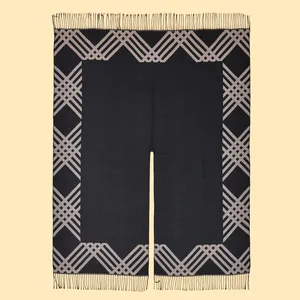 Detailed view of black tassel poncho with grey geometric lattice pattern and fringe