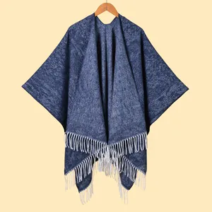 Women's dark blue knitted shawl wrap with white fringe tassels on a wooden hanger