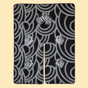 Vue détaillée d'un poncho tricoté noir avec lignes circulaires blanches et motifs de roses
