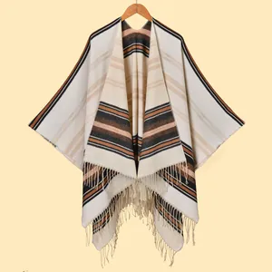 Detail of soft striped knit poncho featuring elegant tassels and earthy neutral tones