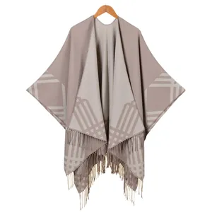 Women's warm faux cashmere poncho featuring a modern geometric plaid pattern and tassel hem