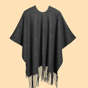 Close-up of a dark grey knitted poncho featuring elegant long fringe hem and soft texture