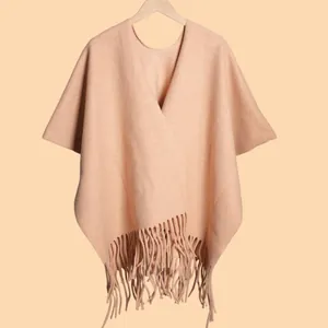 Close-up of beige thick wool shawl featuring fine knit texture and long fringe tassels
