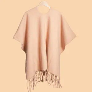 Detail of warm beige cashmere shawl poncho with elegant tassel fringe and wool texture