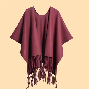 Detailed texture of thick burgundy winter poncho featuring soft fringe tassels on the hem