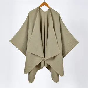 Detail of light khaki knit shawl featuring contrast blanket stitching and premium texture