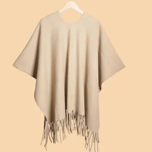 Detailed view of thick beige knit shawl texture with long decorative fringe tassels