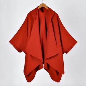 Detail of red knitted hooded poncho showing thick texture and fine stitching on the edges