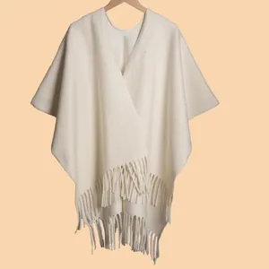 Close-up of cream knit shawl featuring long tassel fringe and elegant V-neck design