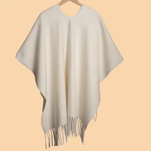 Detailed view of cream knit poncho featuring soft tassel fringe and cozy texture