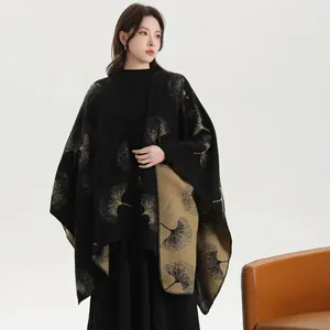 Detail of knit shawl featuring golden ginkgo leaf pattern on black and khaki fabric
