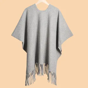 Detail of grey wool-feel poncho shawl featuring elegant fringe hem and round neckline